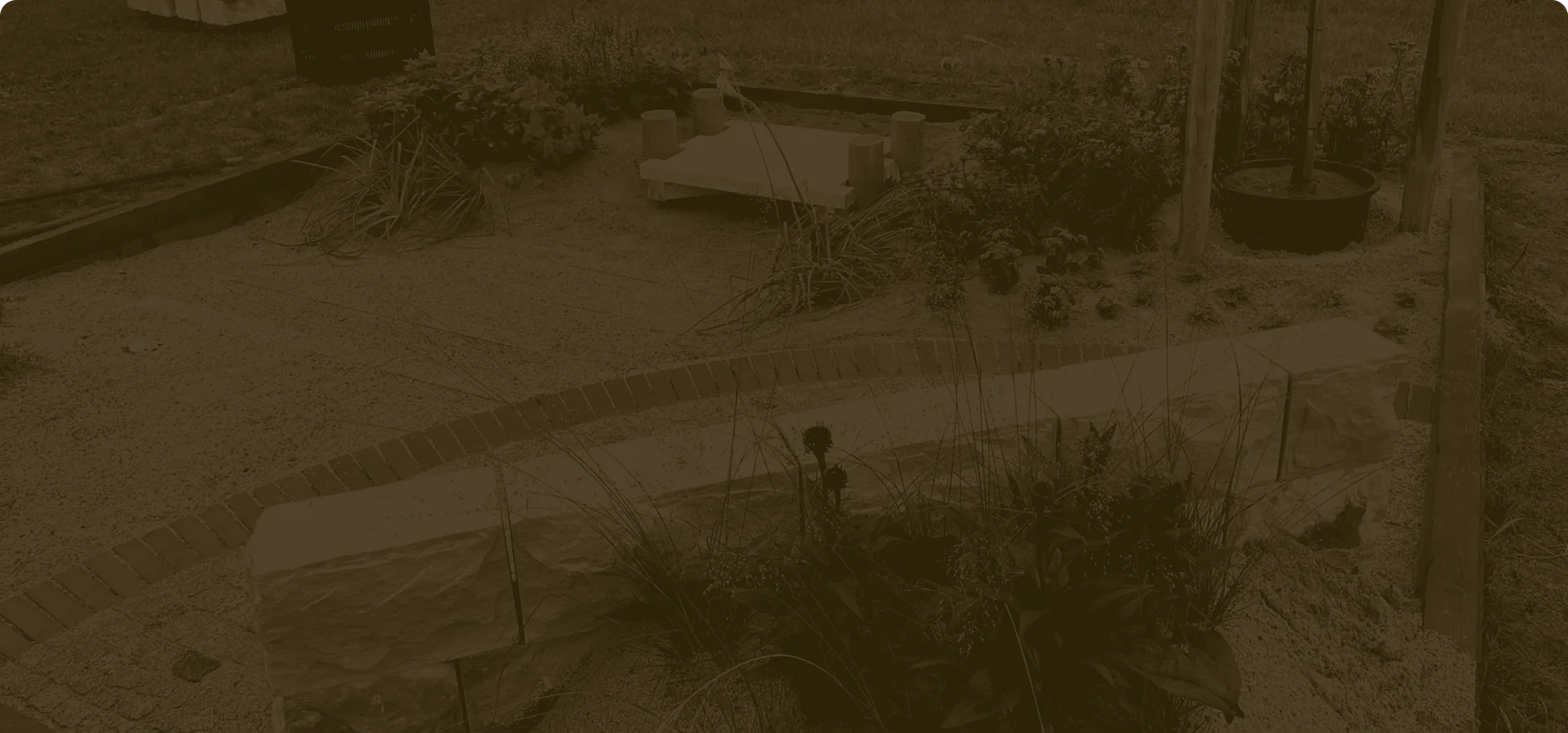 Neu angelegter Garten mit Sandsteinmauer, Klinkerweg und jungen Stauden