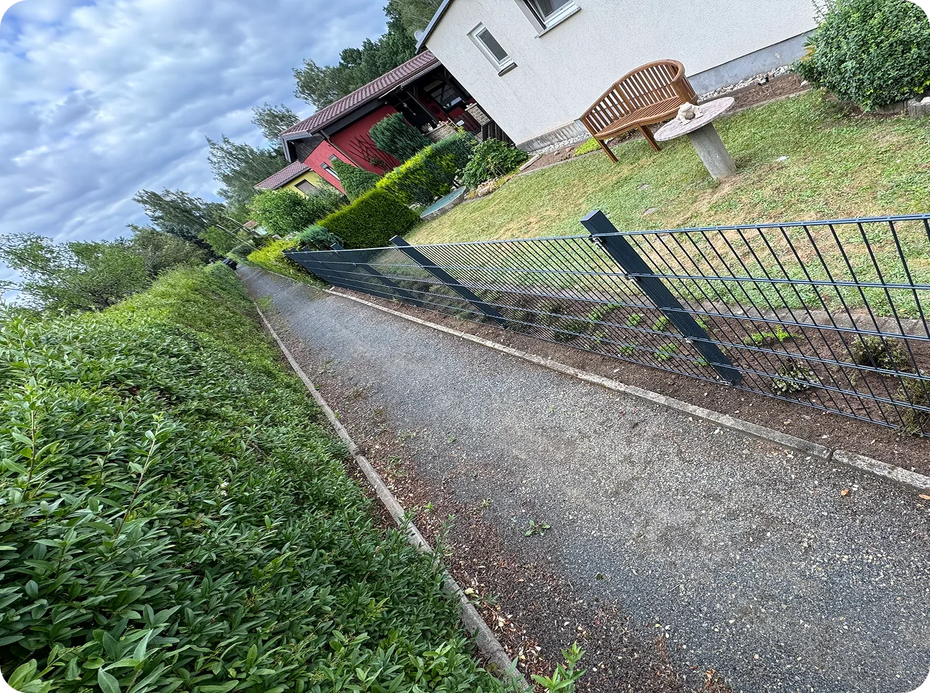 Doppelstabmattenzaun zwischen Fußweg und Rasen, daneben eine Kirschlorbeerhecke