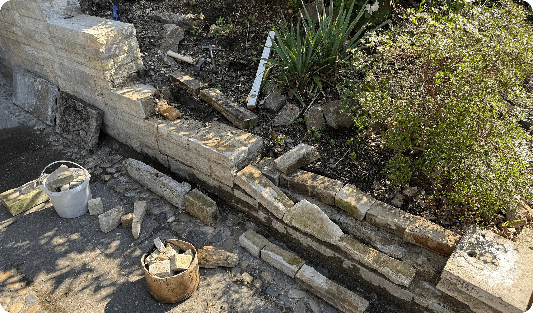 Vorher: eingestürzte Sandsteinmauer mit losen Steinen am Gartenweg