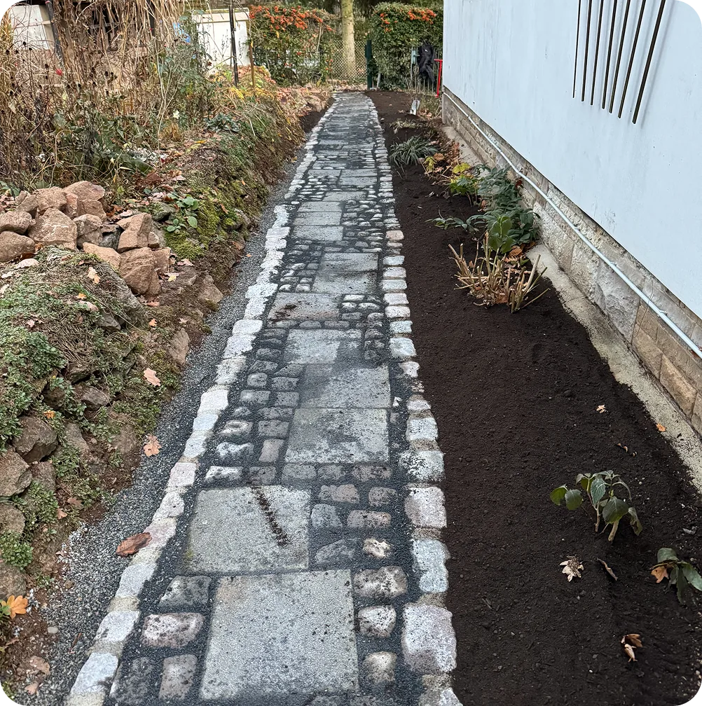 Nachher: Weg aus Granitplatten und Pflaster mit neuem Beet an der Hauswand