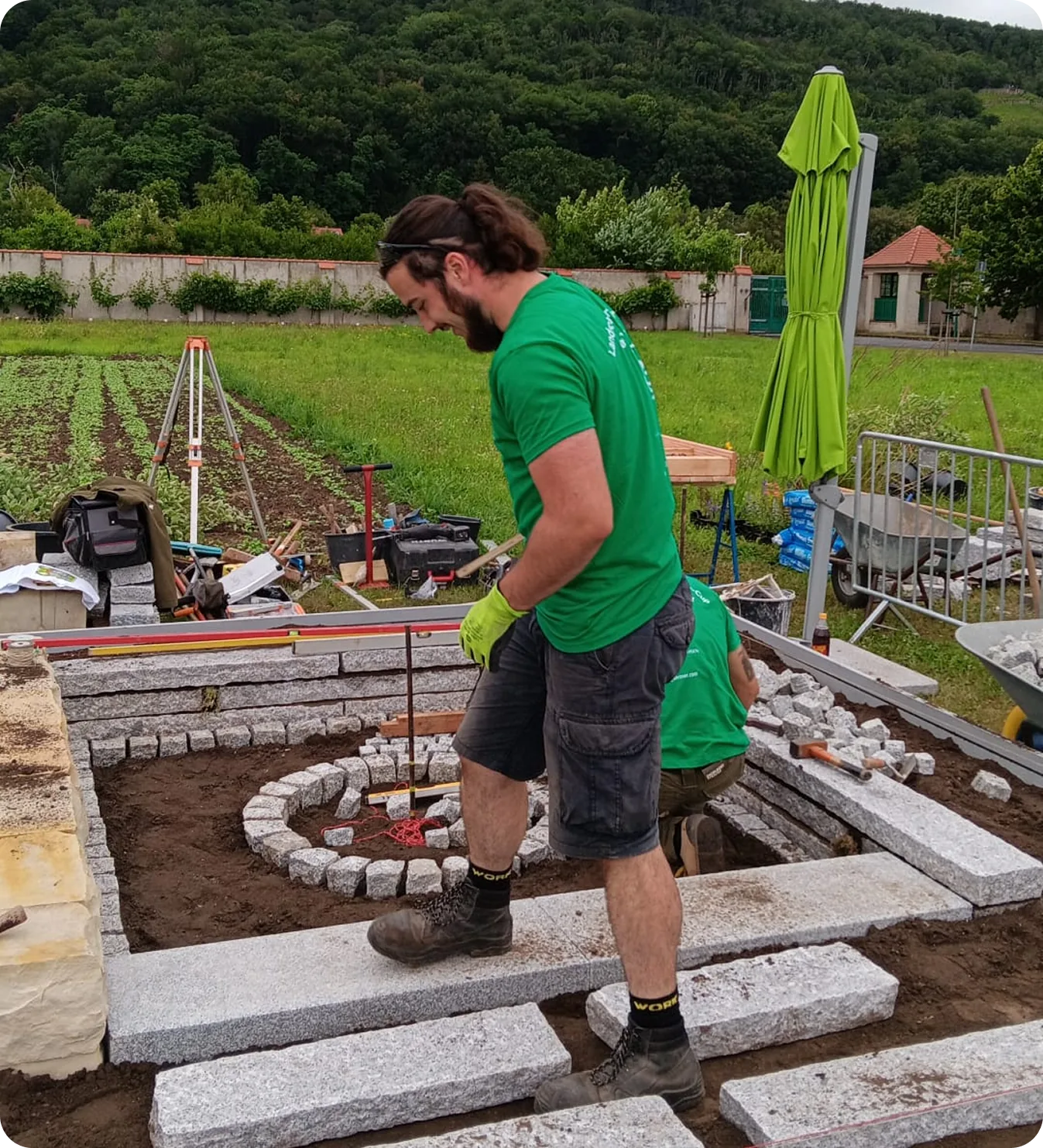 Gärtner beim Setzen von Granitblöcken für eine Kräuterspirale